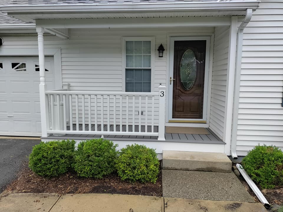 A white house with a porch and a brown door