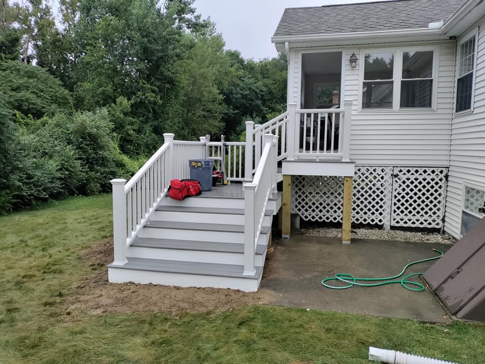 A white house with a deck and stairs in the backyard.