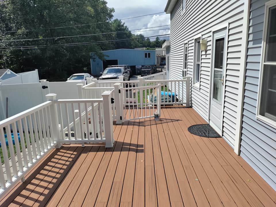 A large deck with a white railing on the side of a house