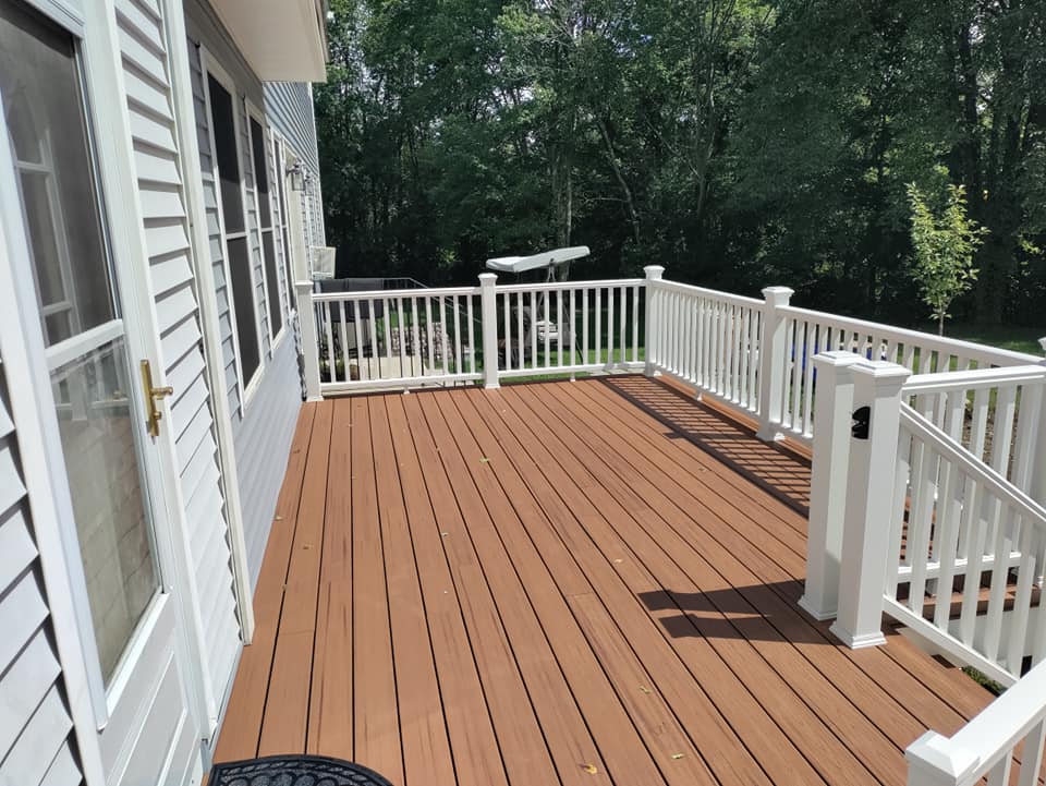 A large wooden deck with a white railing on a house.