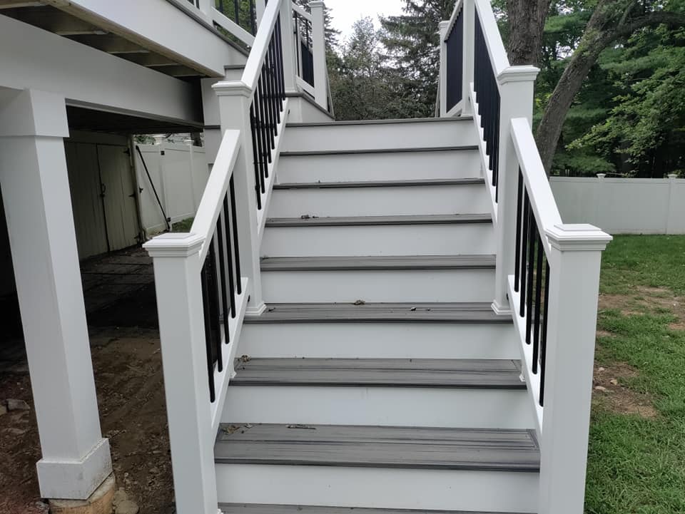 A set of stairs leading up to a deck with a white railing