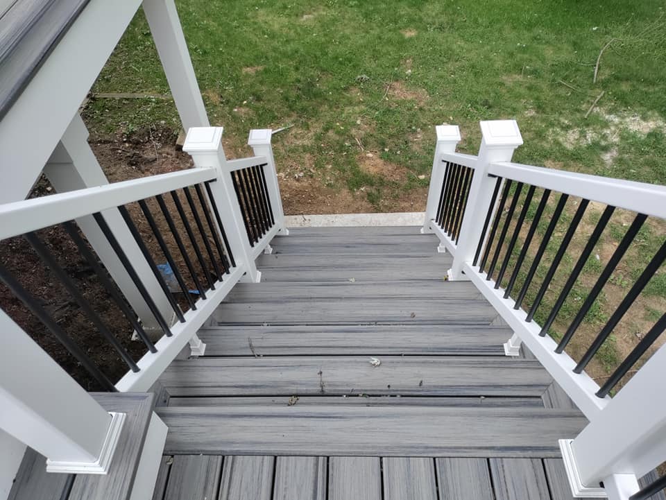 A deck with stairs leading up to it and a black railing.
