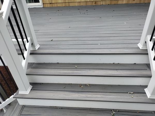 A wooden deck with stairs and a white railing.