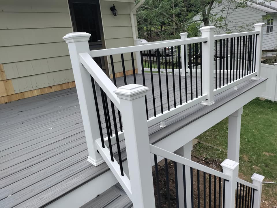 A white deck with black railing and stairs leading up to it.