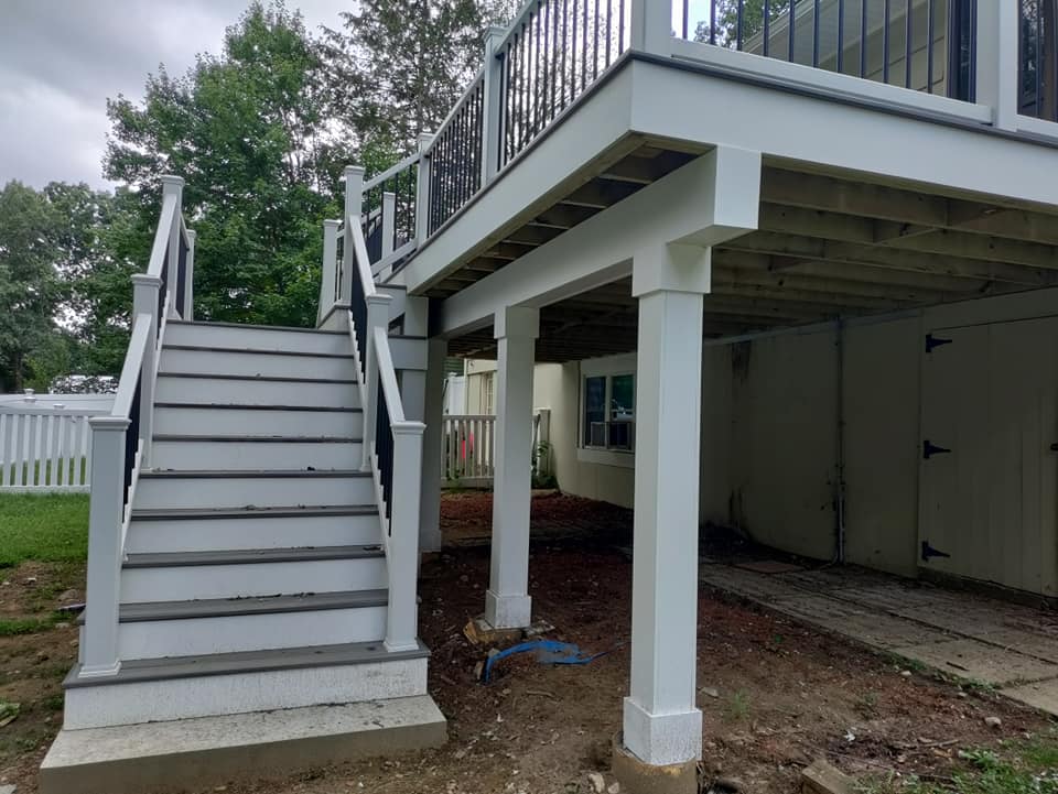 A white deck with stairs leading up to it.