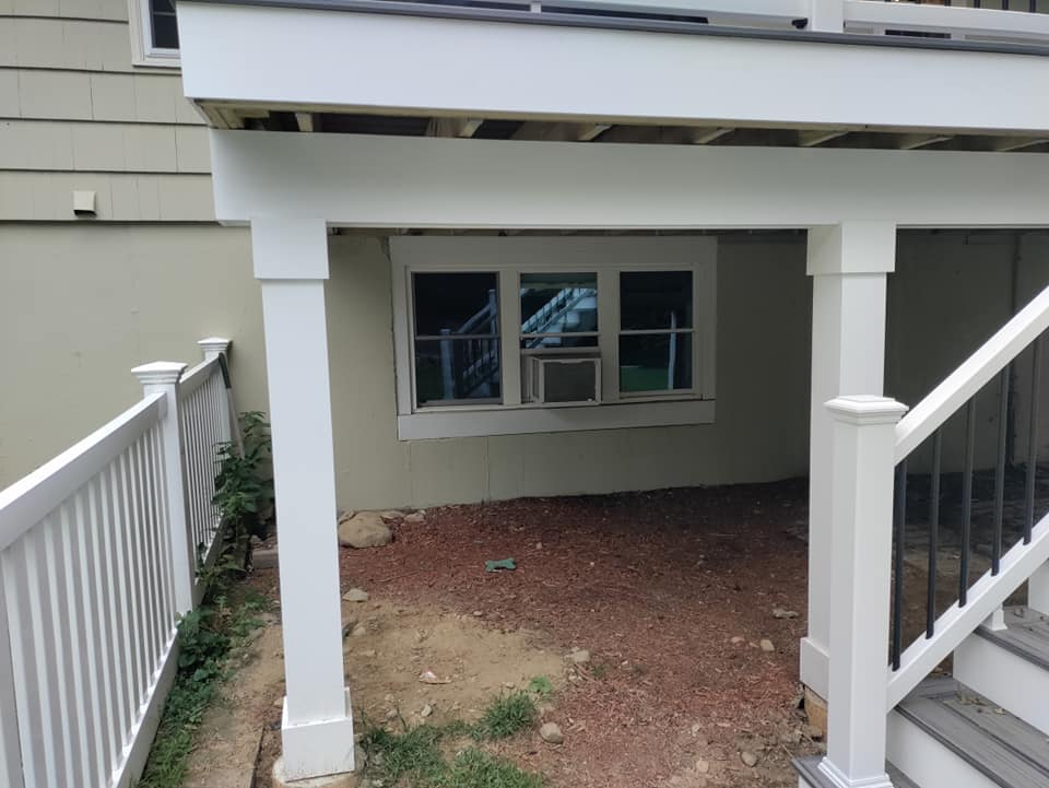 A white deck with a window and stairs underneath it.