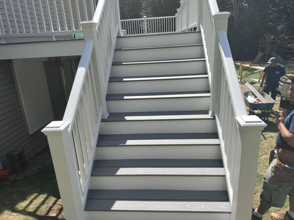 A man is standing next to a set of stairs leading up to a deck.