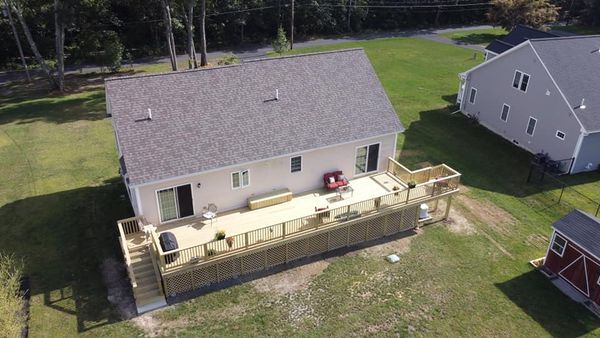 An aerial view of a house with a large deck in the backyard.
