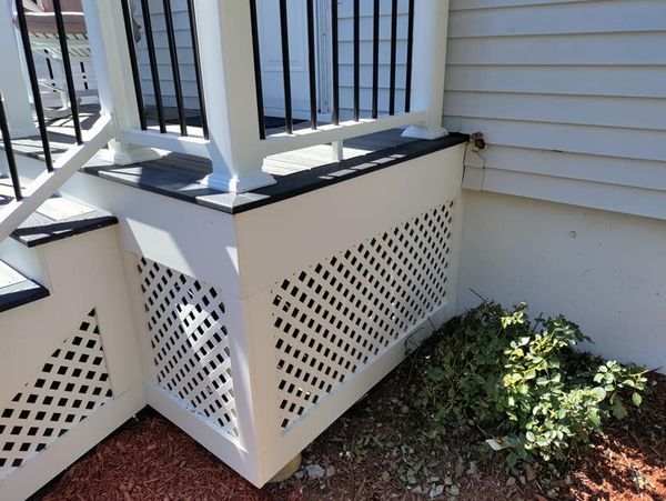 A white porch with stairs and a black railing