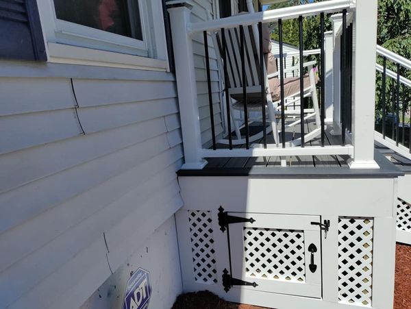 A white house with a rocking chair on the porch.