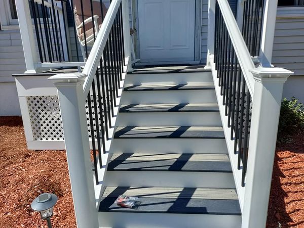 A set of stairs leading up to a house with a black railing
