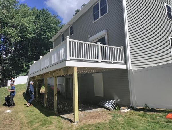 A man is standing in front of a house with a deck.