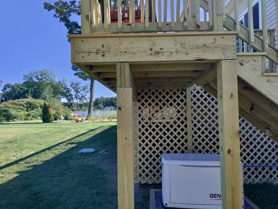 A wooden deck with stairs and a generator underneath it.