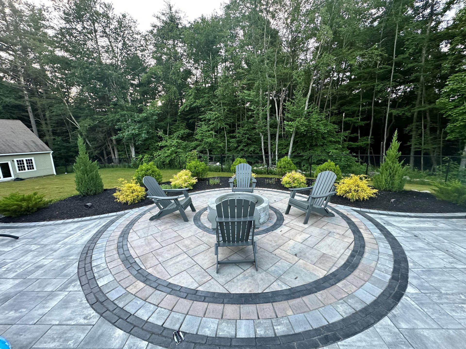 A patio with chairs and a fire pit in the middle of it.