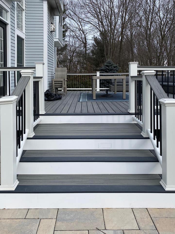 A deck with stairs leading up to it and a white railing.