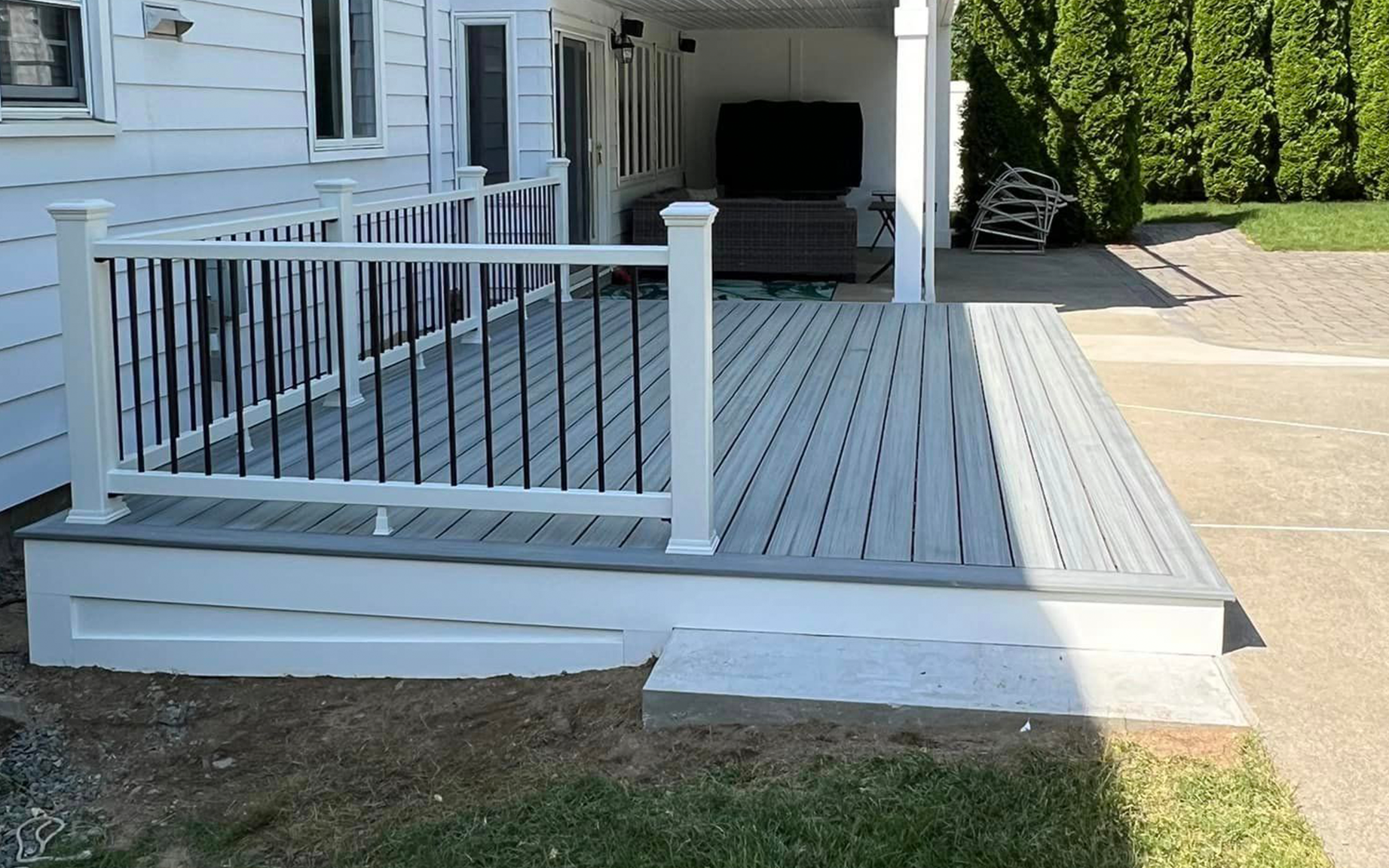 The backyard of a house with a large deck and chairs.