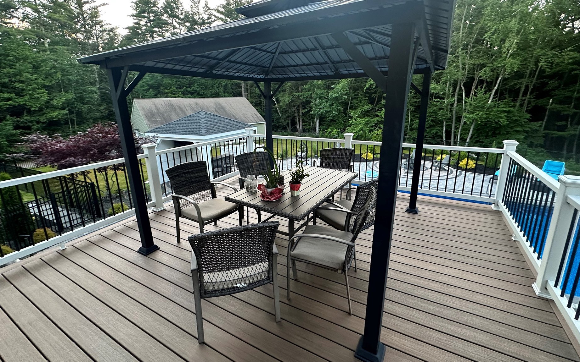 A deck with a table and chairs under a gazebo.