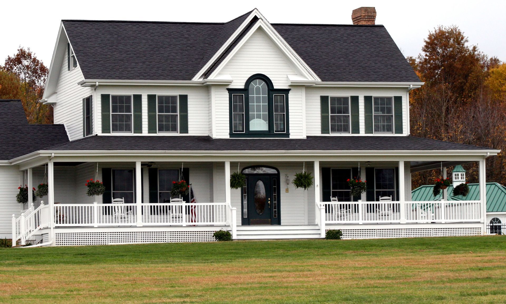 A large porch with chairs and a bench in front of a house.