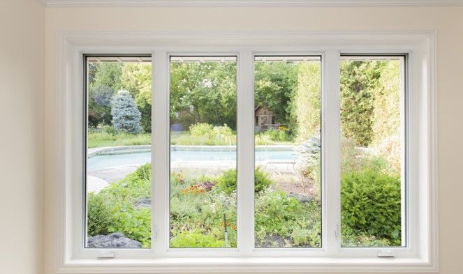 A large white window with a view of a garden.