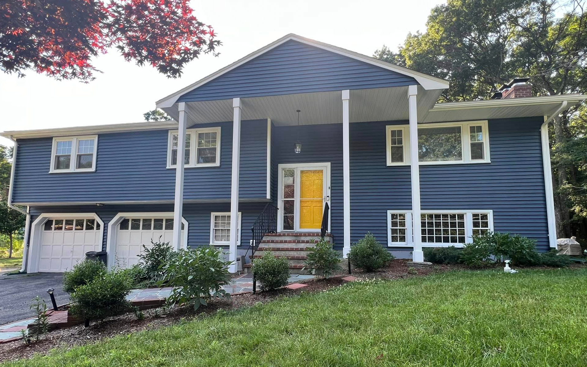 A large porch with chairs and a bench in front of a house.