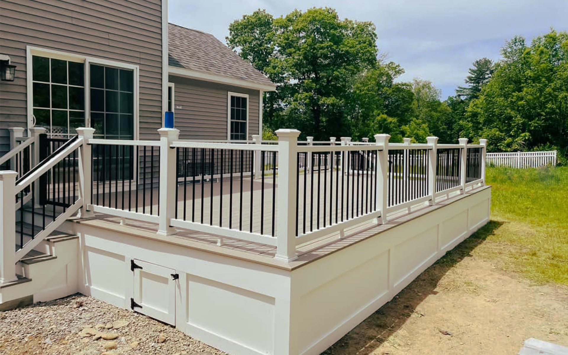 A white deck with a black railing is in front of a house.