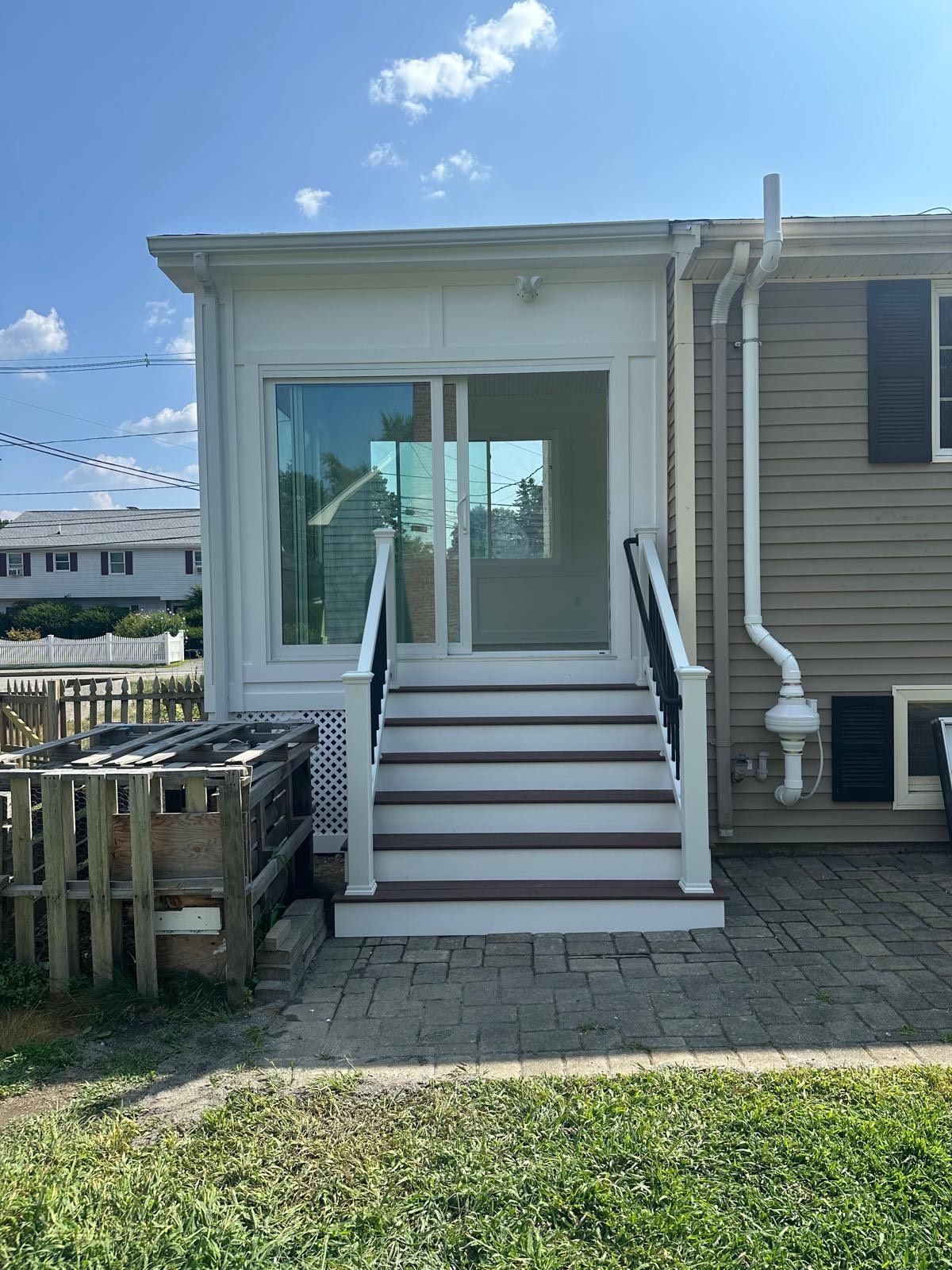 Backyard deck with steps leading to a room with sliding glass doors.