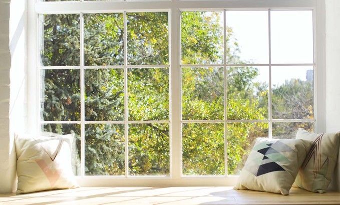 A window seat with pillows and a view of trees.