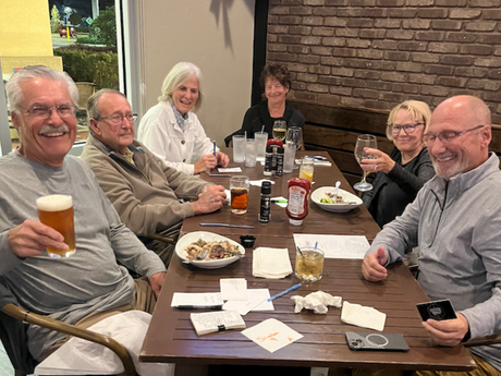 A group of people are sitting at a table with food and drinks.