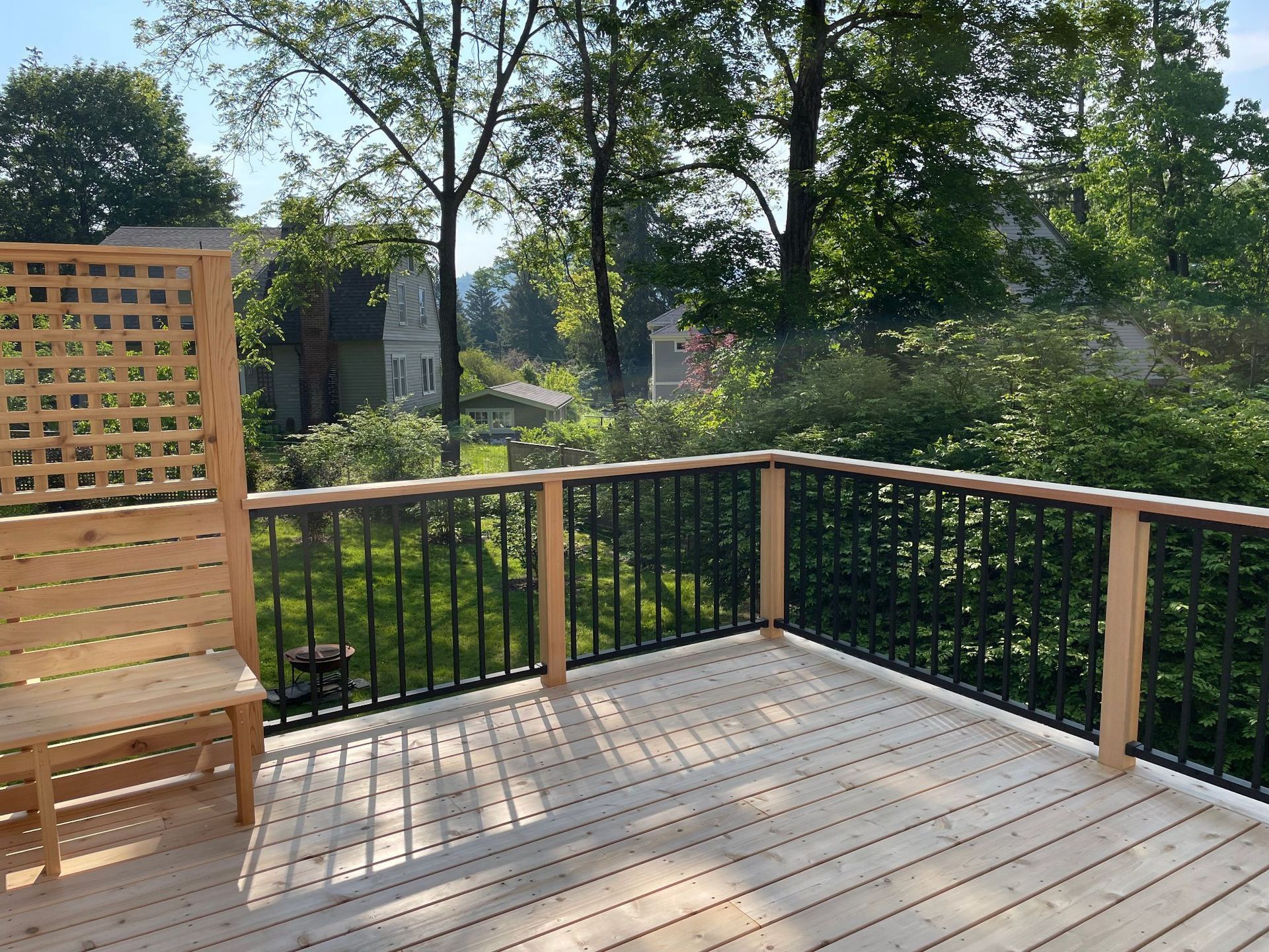A wooden deck with a black railing and a bench.