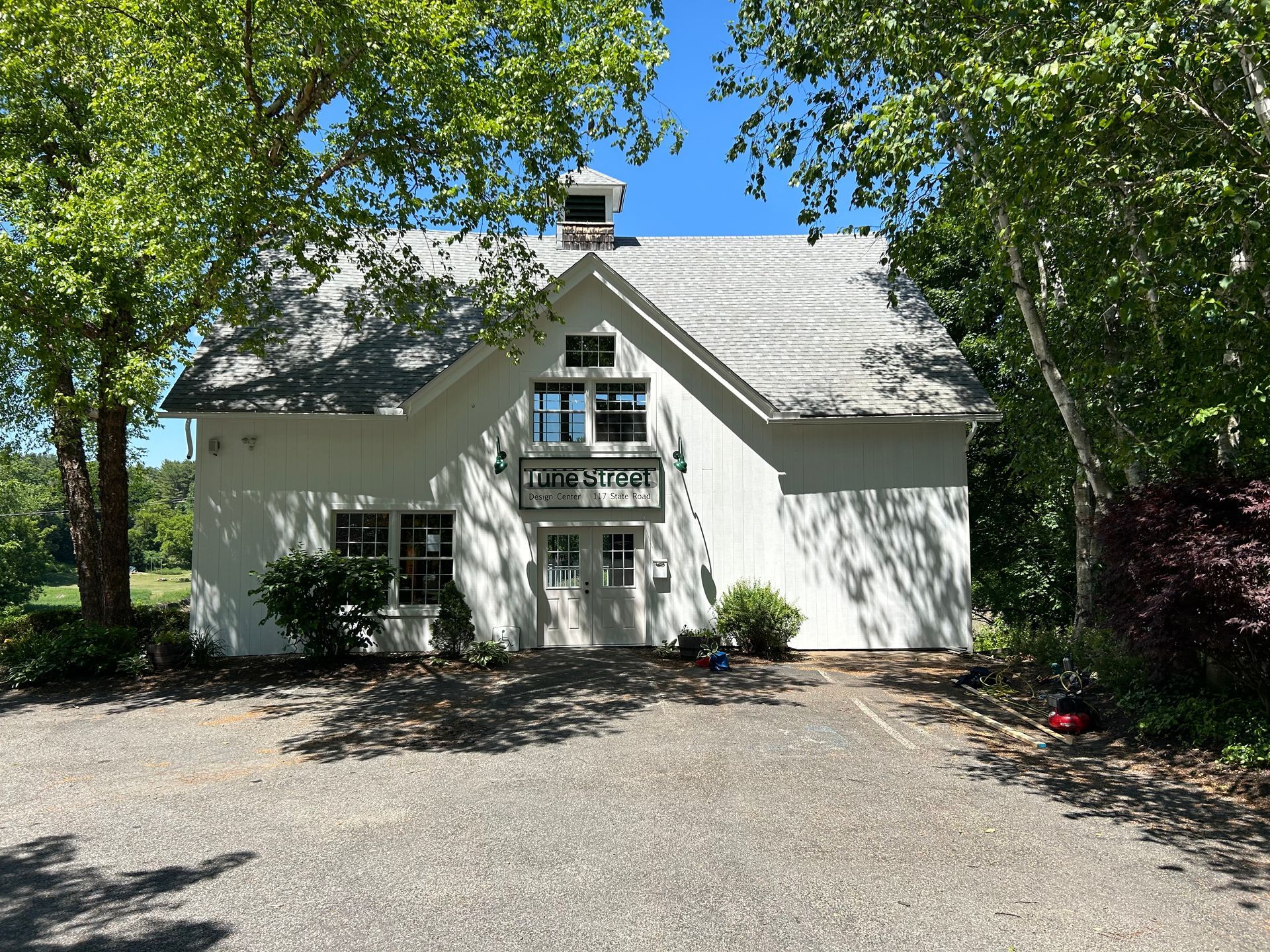 A white house with a gray roof is surrounded by trees