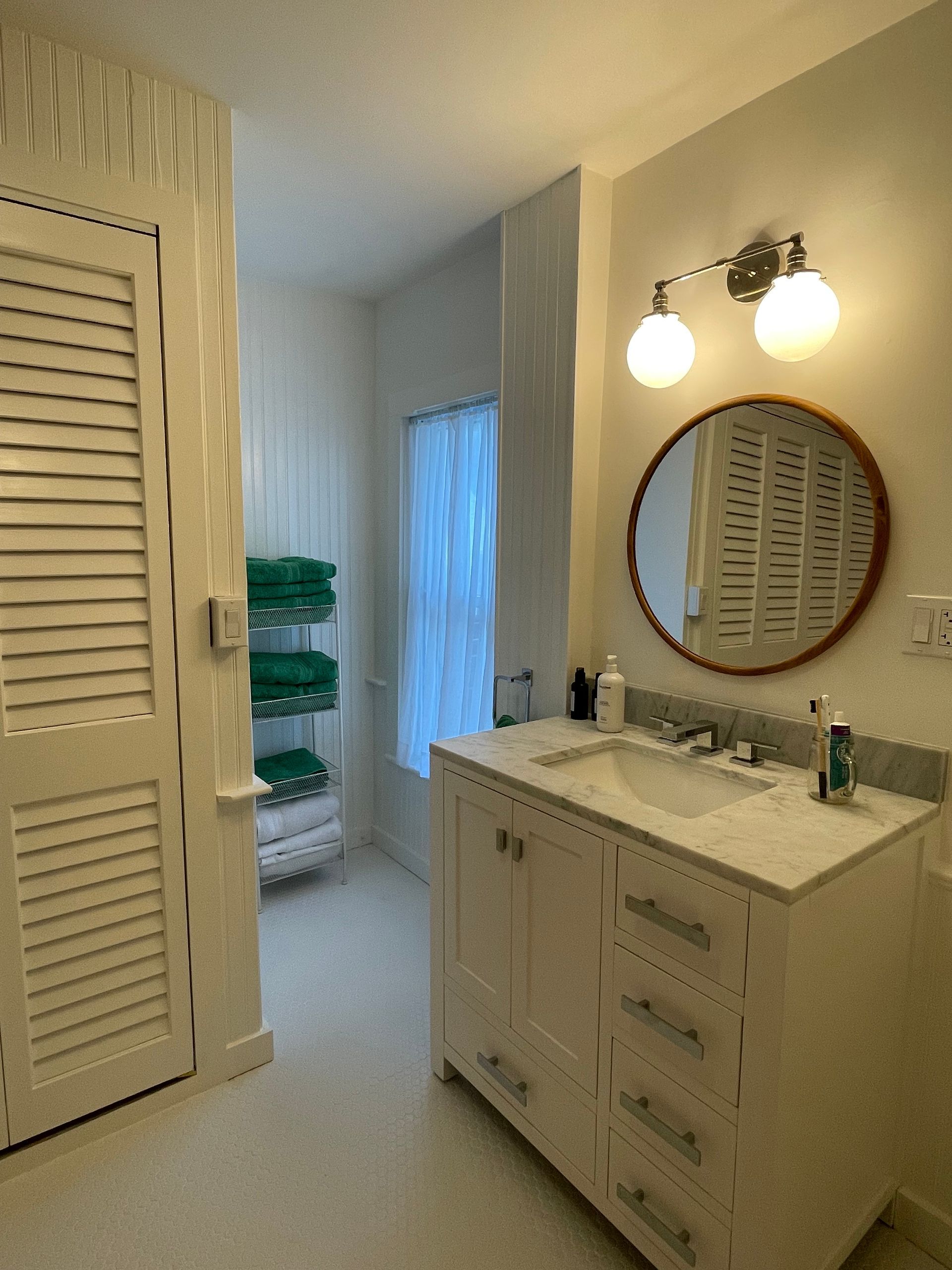 A bathroom with a sink and a round mirror