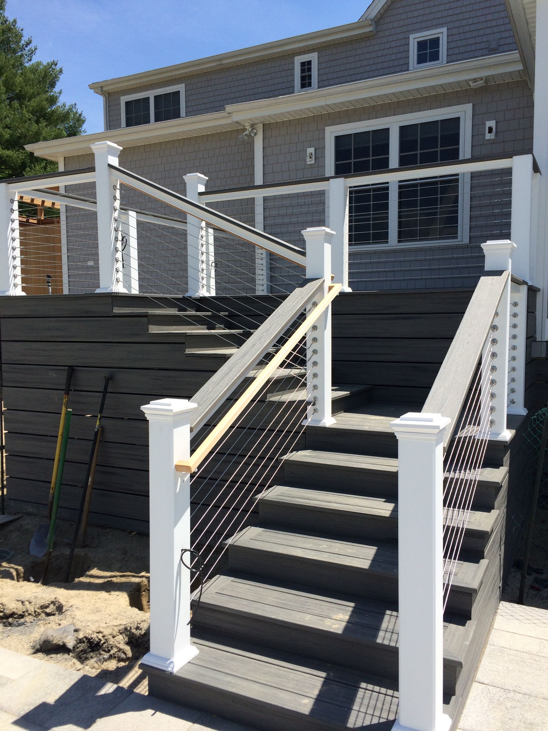 A deck with stairs leading up to it and a house in the background