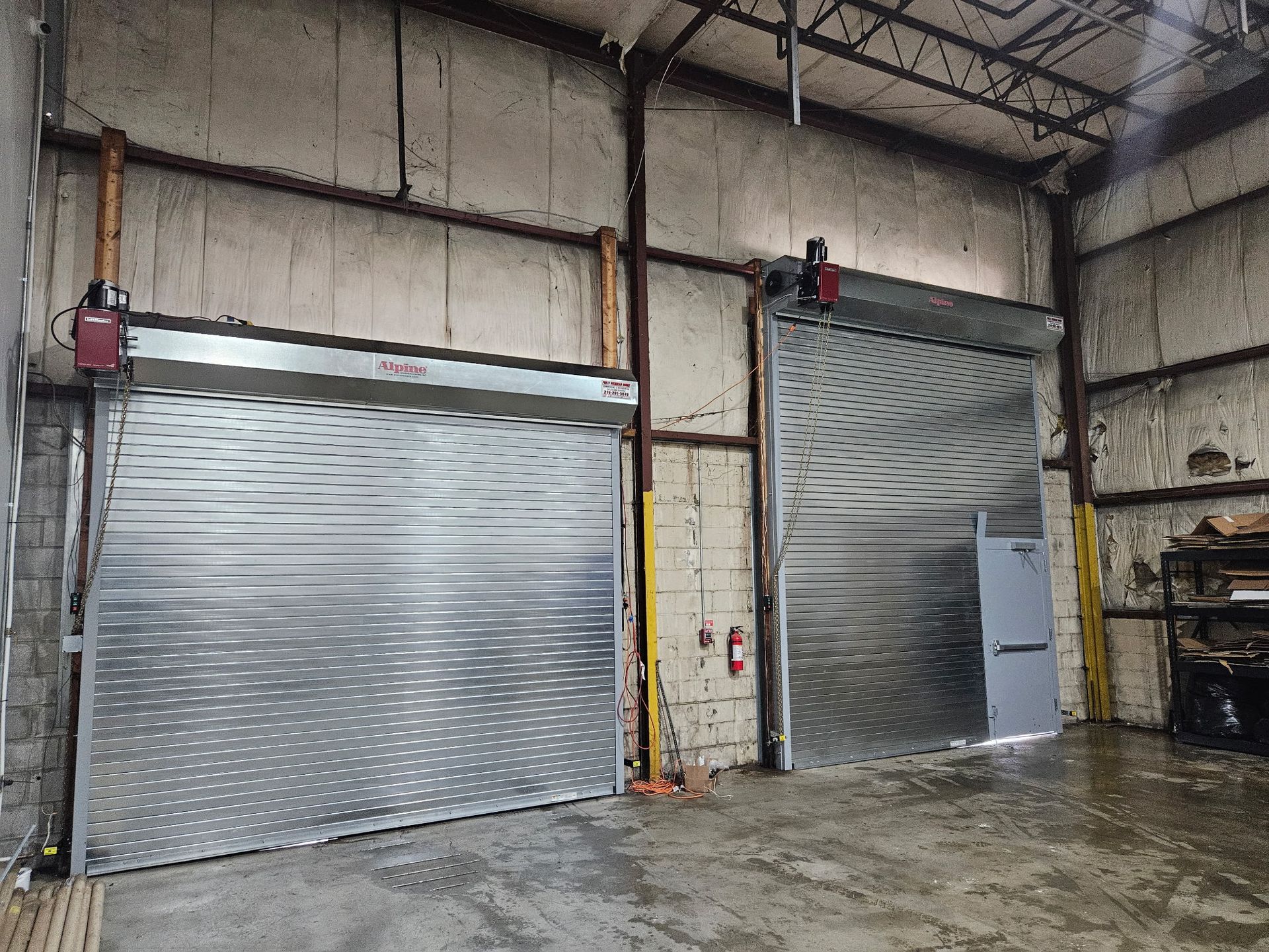 Two closed, metallic rolling overhead doors inside a commercial building.