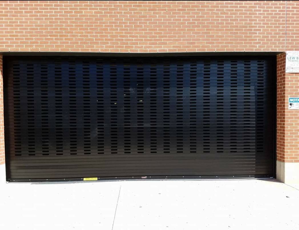 Black security gate on a brick building with horizontal vent slots.
