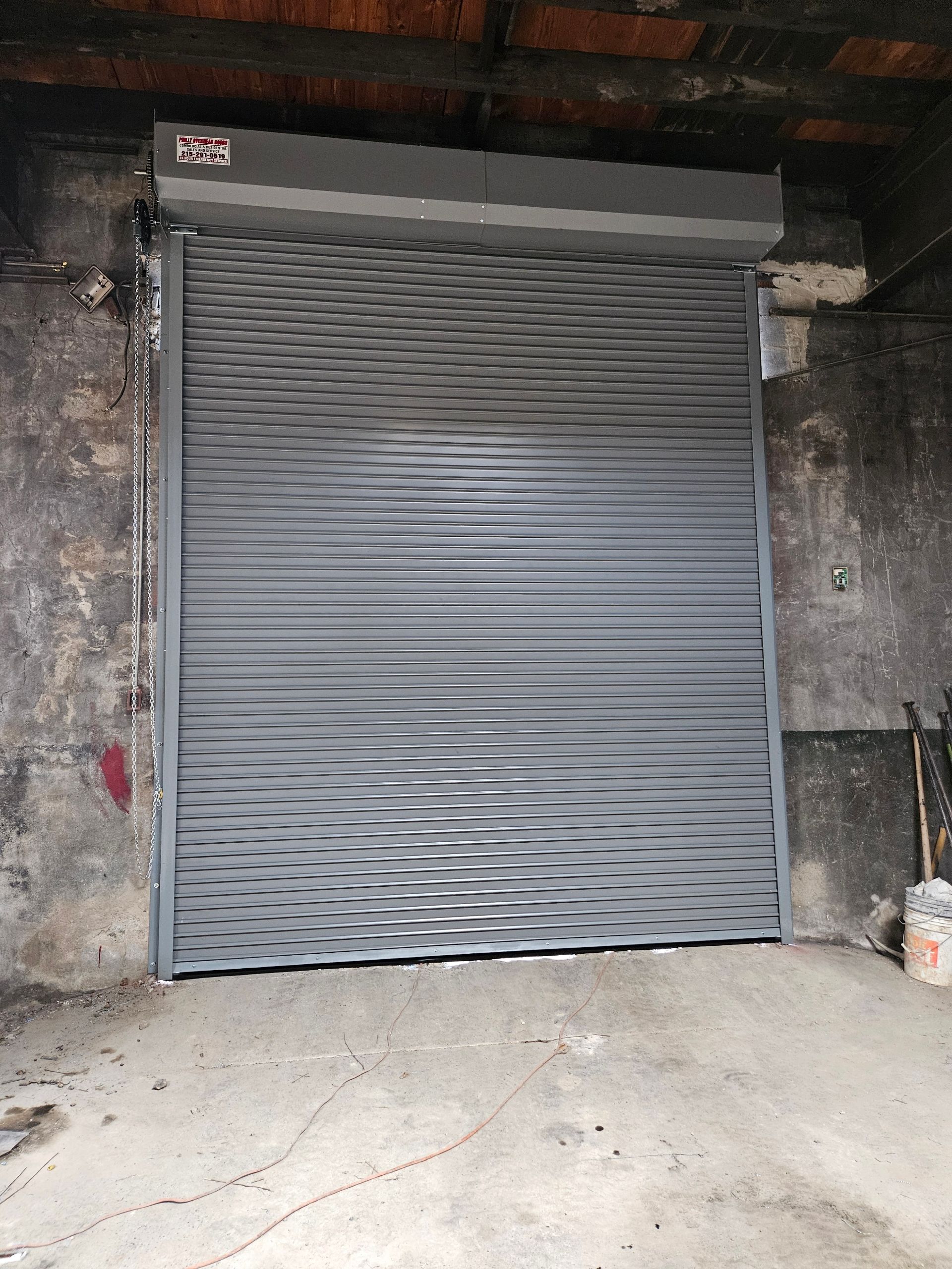 Gray metal roll-up security door in a concrete opening.