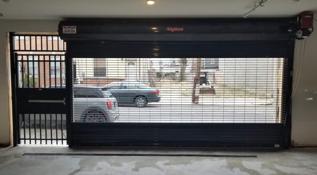 Dark gray security gate open, revealing a street scene with cars and a building.