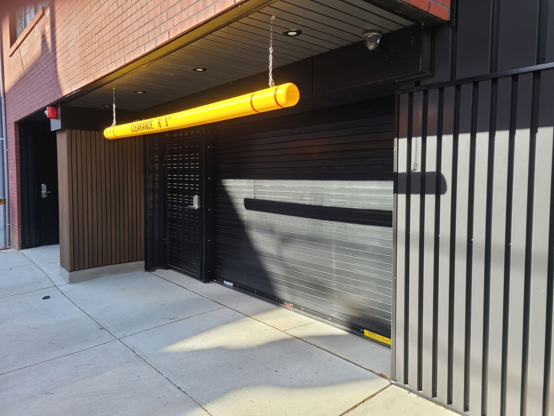 Entrance to garage with a yellow height bar and black security gate.