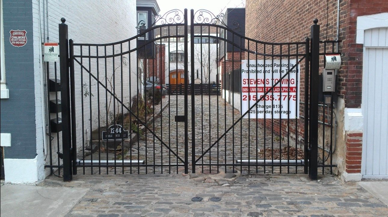 Black metal gate in a narrow brick alleyway. 