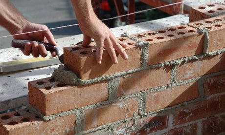 a person is laying bricks on a wall with a trowel