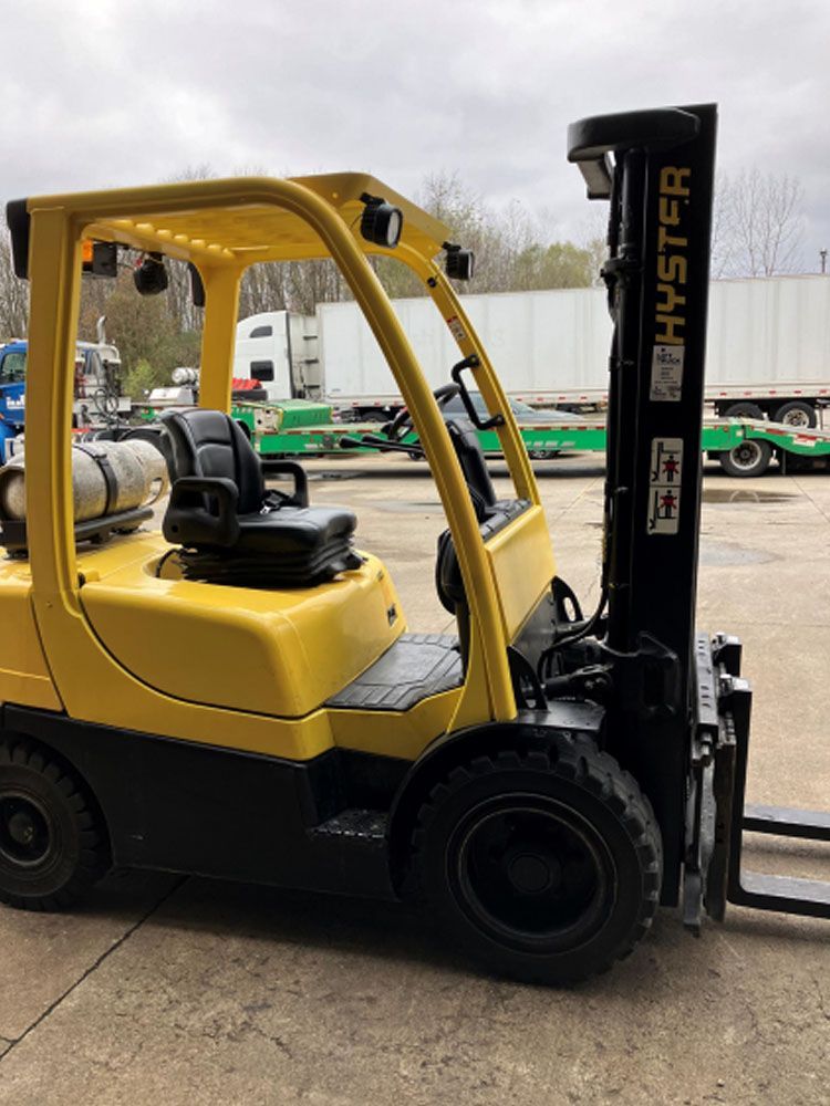 A yellow forklift is parked in a parking lot.