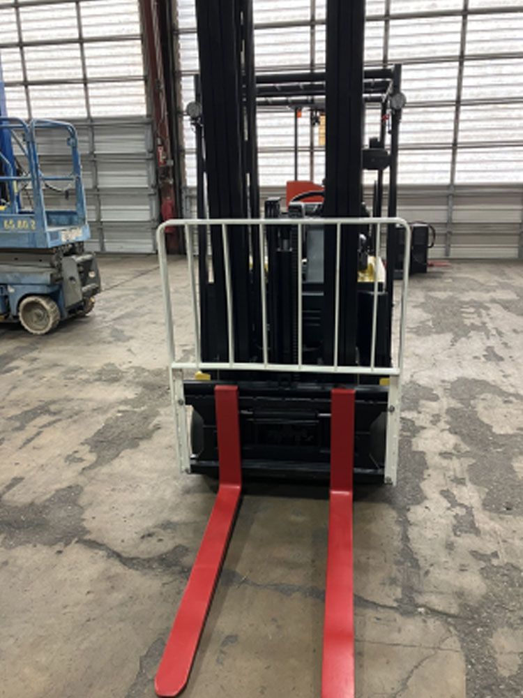 A forklift with red forks is parked in a garage.