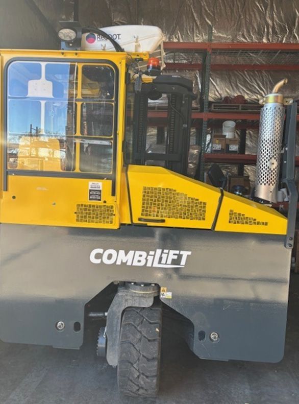 Yellow and gray Combilift forklift. Side view, parked indoors.
