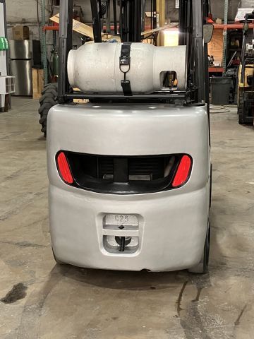 A forklift with a propane tank on the back is parked in a warehouse.