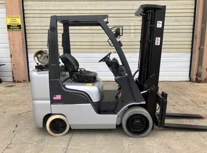 A forklift is parked in front of a garage door.