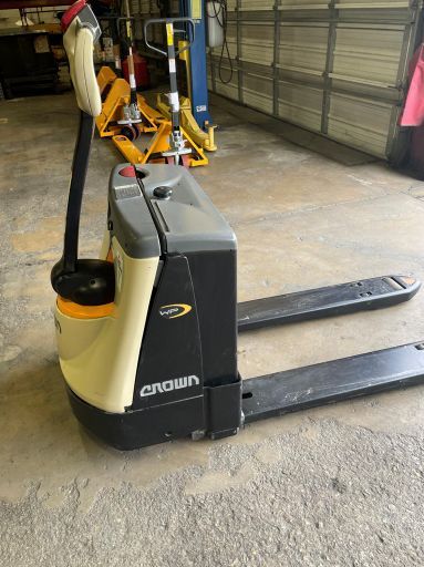 A pallet truck is sitting in a garage next to a garage door.