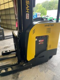 A yellow and black forklift is parked in front of a garage door