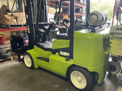 A green forklift is parked in a warehouse