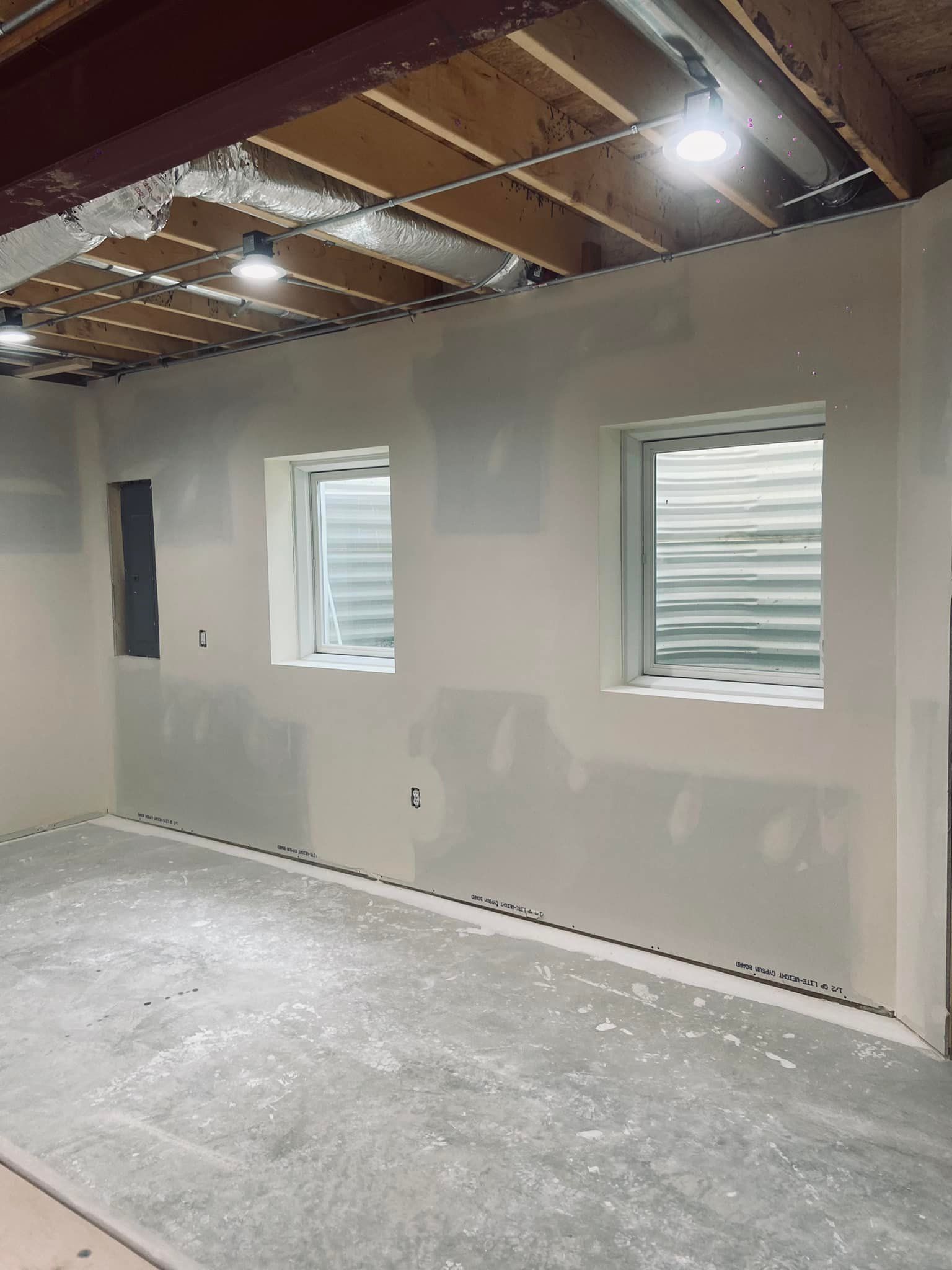 A room with two windows and a ceiling in a building under construction.