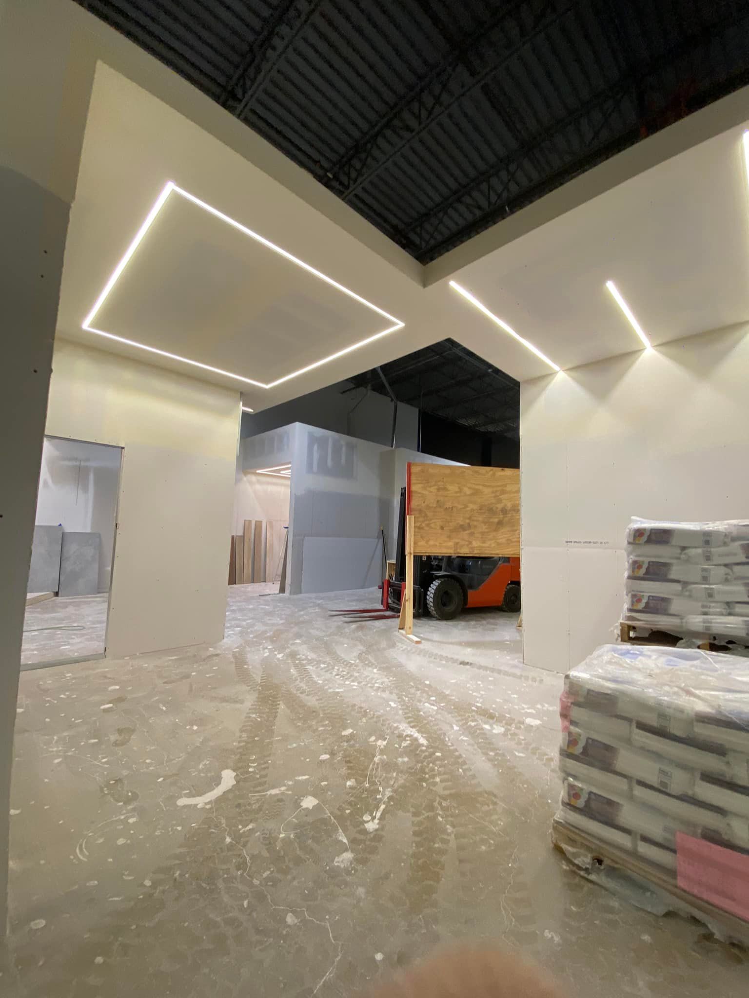 A warehouse with a lot of bags of cement and a forklift in the background.