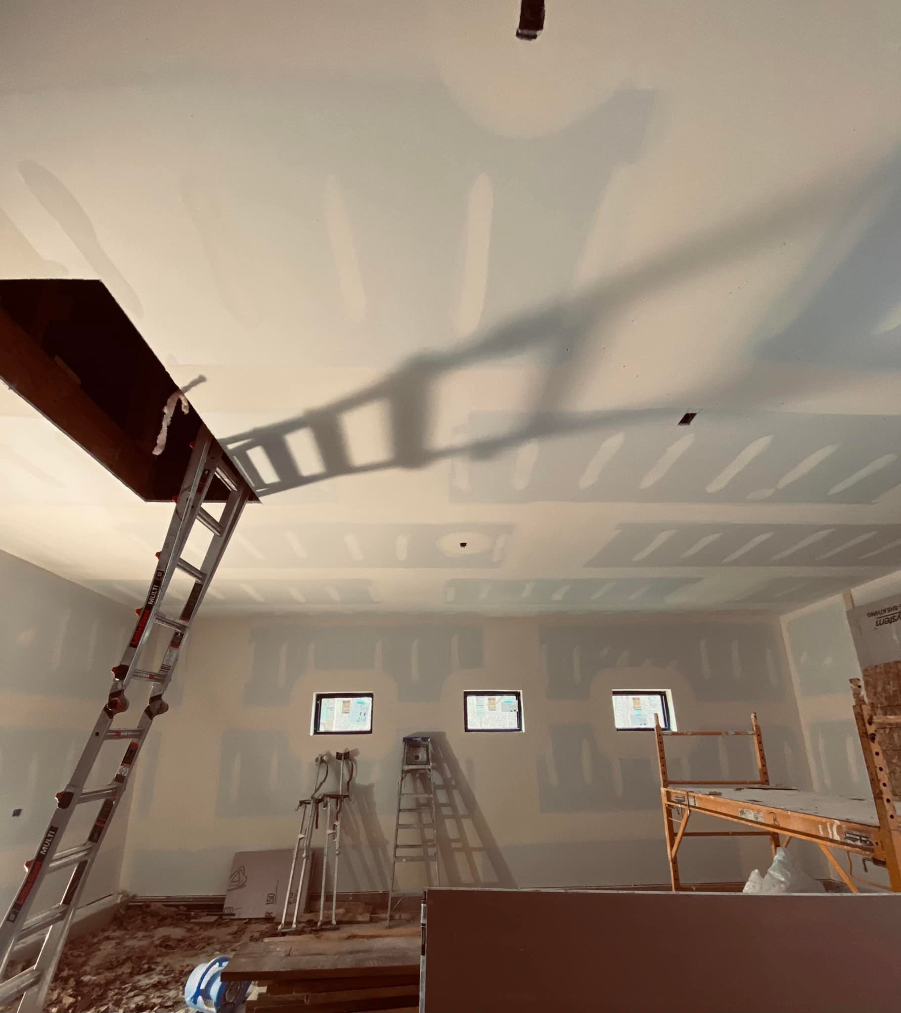 A ladder is hanging from the ceiling of a room under construction.